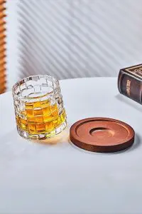 verre à whisky tumbler posé à côté d’un socle en bois sur une table blanche