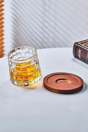 verre à whisky tumbler posé à côté d’un socle en bois sur une table blanche