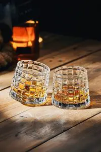 deux verres à whisky tumbler posés sur une table en bois, l’un légèrement incliné