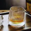 Verre à whisky tumbler vintage en verre nervuré posé sur un plateau en bois