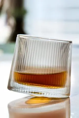 Verre à whisky tumbler nervuré posé sur empilement de planches en bois