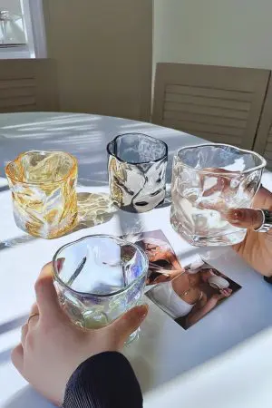 Verres à whisky en cristal teinté sur table – Design ondulé et reflets élégants.