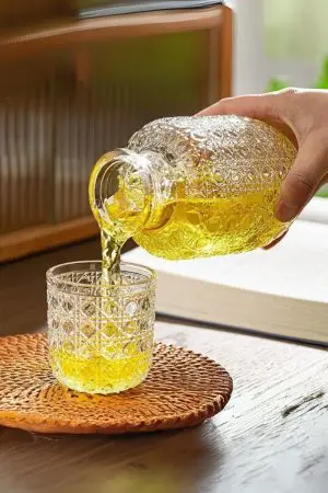 carafe à whisky vintage et verre assorti en verre gravé posés sur une table avec boisson jaune