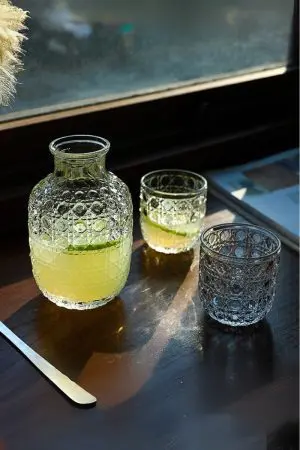carafe à whisky vintage et deux verres assortis sur table bois, boisson jaune et citron vert
