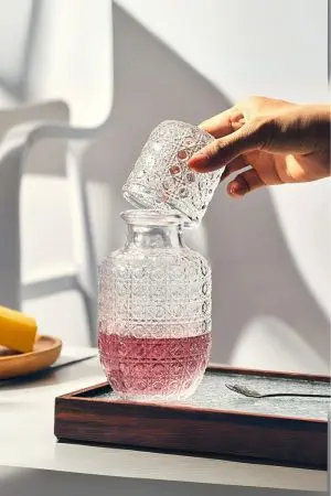 carafe à whisky vintage en verre gravé avec boisson rose, verre posé sur la carafe