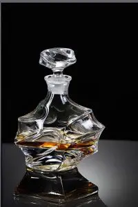 carafe à whisky en cristal design géométrique posée sur une table, boisson ambrée