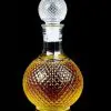 carafe à whisky ronde en verre 1 litre faceted sphere sur table en bois, bouteille sphérique à motifs facettés et bouchon assorti, lumière naturelle ambiance salon chic