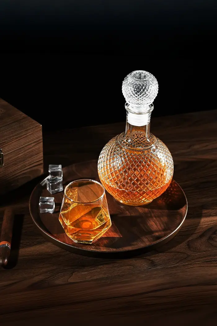 carafe à whisky ronde en verre faceted sphere motif diamant, bouteille sphérique pleine de whisky, bouchon boule en verre assorti, fond noir élégant