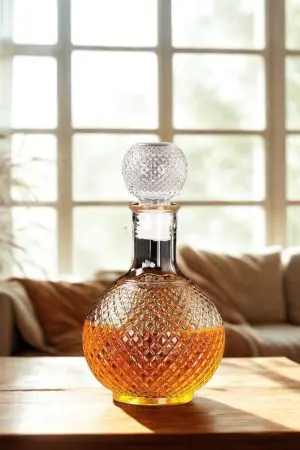 carafe à whisky ronde faceted sphere en verre 1 litre remplie de whisky, bouchon boule en verre, posée sur table en bois foncé, ambiance bar rétro