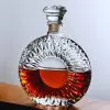 carafe à whisky ronde en verre taillé, posée sur une table en bois avec un liquide ambré