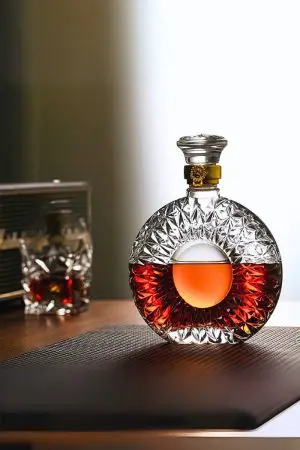carafe à whisky ronde en verre taillé posée sur une table, remplie de whisky ambré, avec verre assorti en arrière-plan flou