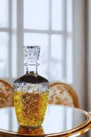 carafe à whisky vintage 800ml en verre design étoilé, remplie de whisky, mise en scène sur table élégante devant une fenêtre