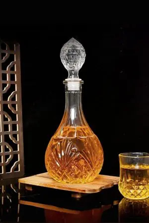 carafe à whisky cristal 800ml avec bouchon lotus sculpté, décor floral gravé, whisky ambré à l’intérieur, ambiance élégante sur fond boisé