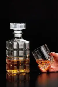 carafe à whisky rayé en verre 800ml design diamond grenade avec rayures verticales et bouchon assorti, remplie de whisky doré, fond noir