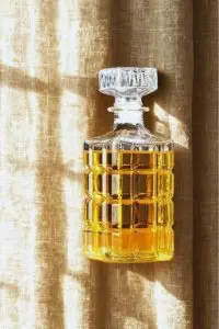 carafe à whisky rayé en verre 800ml design diamond grenade posée devant un fond marbré, remplie de whisky ambré, bouchon sculpté visible