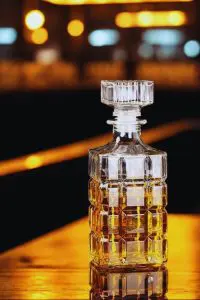 carafe à whisky rayé en verre 800ml design diamond grenade posée sur un comptoir de bar, reflets dorés et ambiance lumineuse en arrière-plan