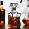 carafe à whisky en verre taillé, remplie de whisky ambré, posée sur une table en bois