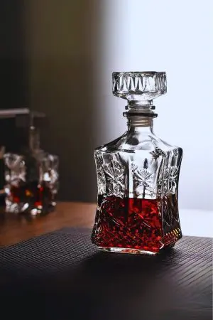 carafe à whisky en verre taillé, à moitié remplie de whisky ambré, posée sur un set de table