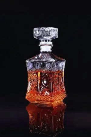 carafe à whisky carrée en verre taillé, remplie de whisky ambré, sur fond noir