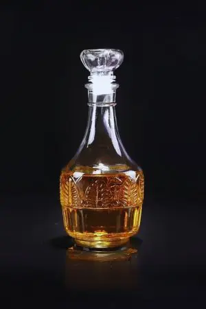 Carafe à whisky ronde en verre gravé avec deux verres assortis, sur table bois clair