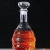 carafe à whisky bombée en verre gravé, remplie de whisky, posée sur table claire