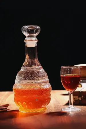 carafe à whisky en verre gravé, remplie de liquide ambré, posée sur une table foncée