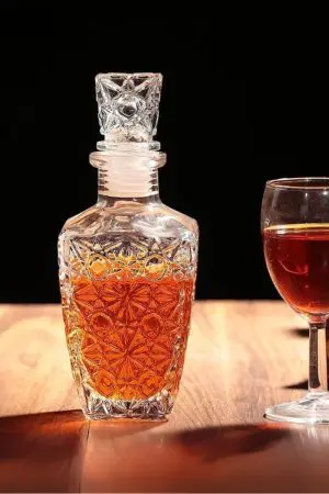 carafe à whisky design en verre gravé Classic Star 500 ml, bouchon assorti, posée sur une table en bois éclairée, verre de dégustation à côté