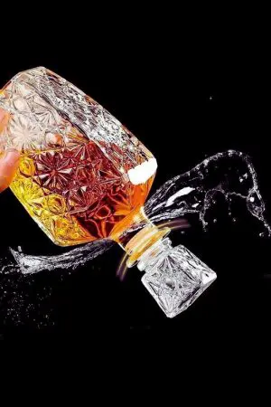 Carafe à whisky rétro en verre gravé inclinée, whisky en train d’être versé.