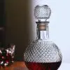 carafe à whisky boule en verre gravé, remplie de whisky ambré, posée sur une surface réfléchissante
