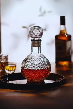 carafe boule à whisky vintage en verre transparent à motifs losanges, remplie de whisky, sur napperon
