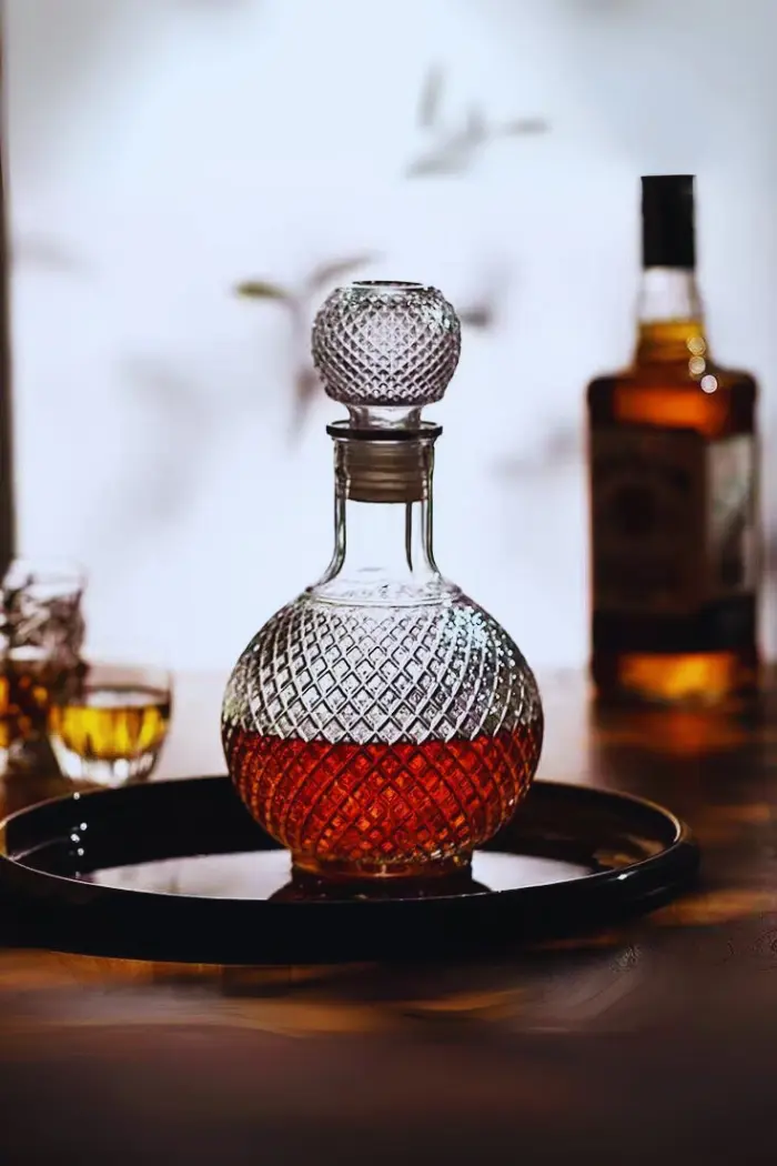 carafe boule à whisky vintage en verre transparent à motifs losanges, remplie de whisky, sur napperon