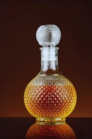 carafe boule à whisky vintage en verre taillé, posée sur surface noire, remplie de whisky