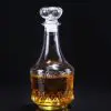 carafe à whisky gravée en verre, remplie de whisky, posée sur une table entourée de verres