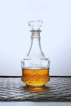 carafe à whisky gravée en verre, remplie de whisky, posée sur fond noir