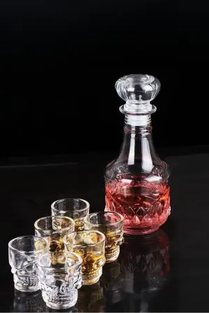 carafe à whisky gravée, remplie de whisky, posée sur une table en bois dans une cuisine lumineuse