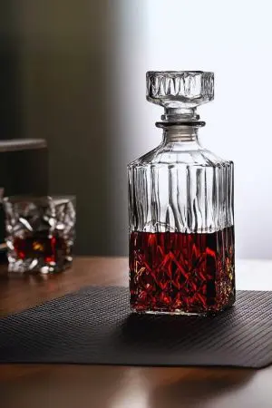 carafe à whisky moderne gravée, remplie de whisky ambré, posée sur une surface en verre
