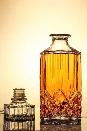carafe à whisky moderne gravée, couchée sur le côté, remplie de whisky, fond jaune