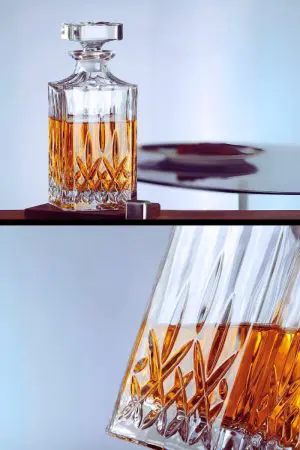 carafe à whisky moderne gravée, bouchon retiré, posée sur fond noir avec un verre assorti
