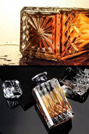 carafe à whisky moderne gravée, remplie de whisky foncé, posée sur un set de table, verre assorti en arrière-plan