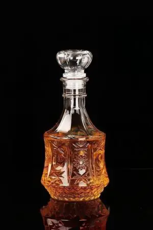 carafe à whisky vintage en verre gravé remplie de whisky sur fond noir