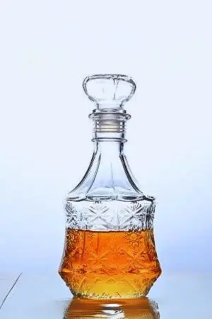 carafe à whisky vintage en verre gravé remplie de whisky, fond clair
