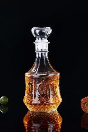 carafe à whisky hexagonale en verre gravé, remplie de whisky, posée sur table en bois