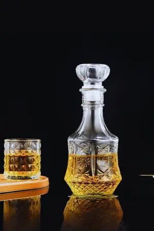 carafe à whisky hexagonale en verre gravé, remplie de whisky, posée sur table en bois