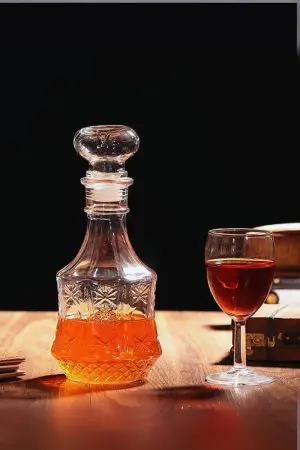 carafe à whisky hexagonale en verre gravé remplie de whisky sur table bois