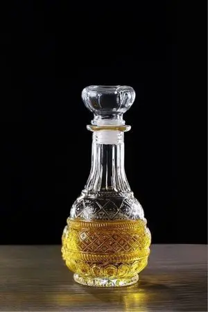 carafe à whisky gravée forme ronde posée, remplie de whisky, fond noir