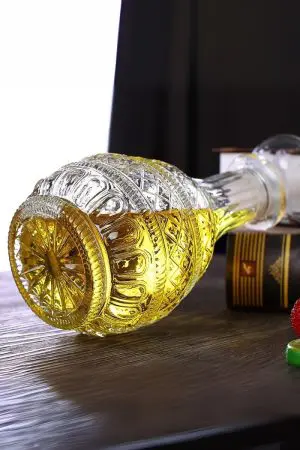 carafe à whisky gravée ronde sur table, remplie de whisky, lumière chaude