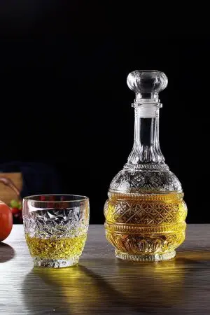 carafe à whisky gravée ronde allongée sur table, remplie de whisky