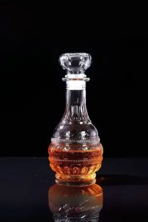 carafe à whisky gravée ronde et verre tumbler sur table, remplis de whisky