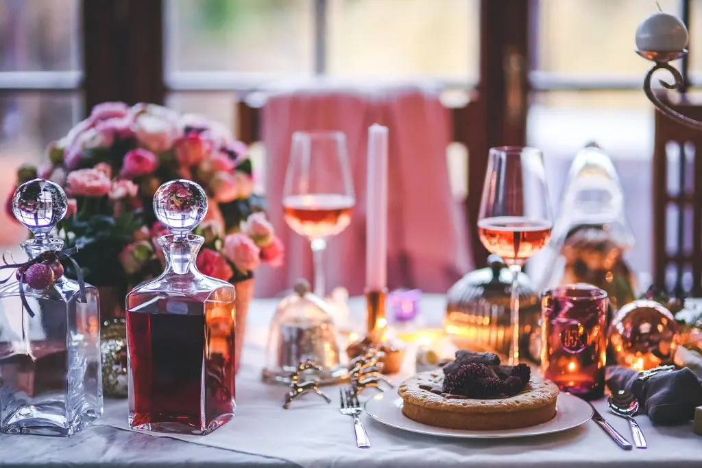 Table de fête élégante avec carafe à whisky, verres à vin rosé et décorations chaleureuses pour un apéritif raffiné.