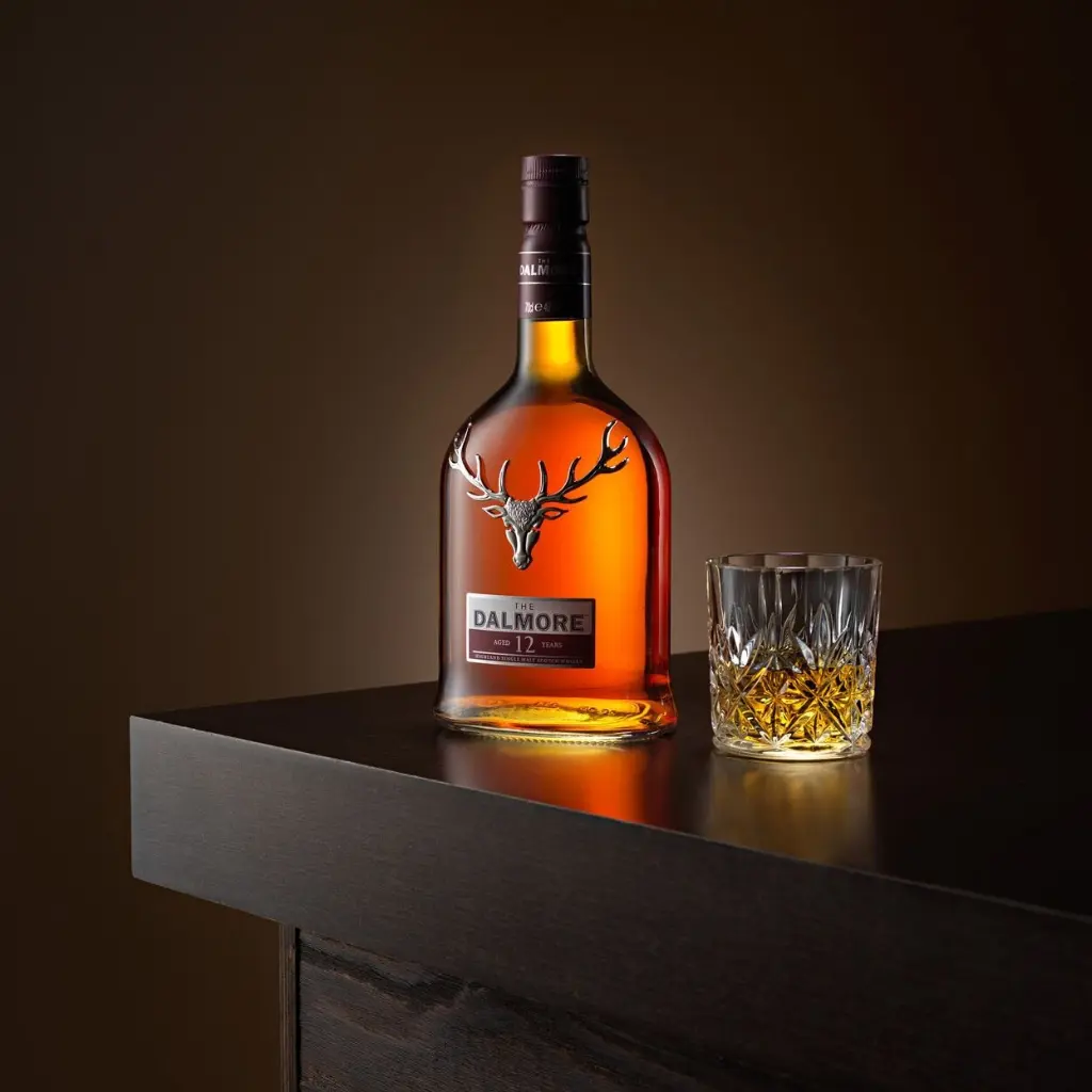 bouteille de whisky The Dalmore 12 ans posée sur une table avec un verre en cristal